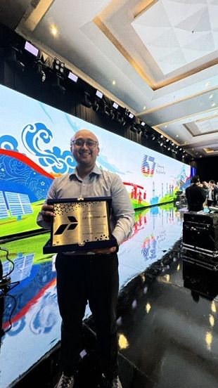 Holding award plaque at Pertamina corporate ceremony