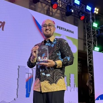 Receiving corporate recognition on stage at Pertamina event